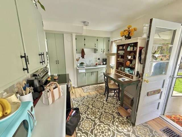 661 E Main St, Stratford, CT 06614 - kitchen with green cabinetry, light wood-type flooring, backsplash, and a sink