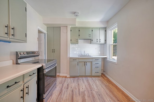 661 E Main St, Stratford, CT 06614 - kitchen with electric range, light wood-style flooring, light countertops, and decorative backsplash
