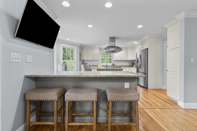 94 Glen Dr, New Canaan, CT 06840 - kitchen with stainless steel refrigerator with ice dispenser, island range hood, a peninsula, a kitchen bar, and recessed lighting