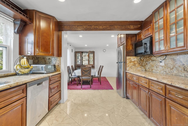 kitchen with appliances with stainless steel finishes, light stone counters, backsplash, recessed lighting, and glass insert cabinets