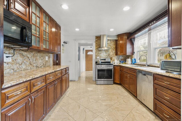 kitchen with appliances with stainless steel finishes, a sink, wall chimney range hood, tasteful backsplash, and recessed lighting