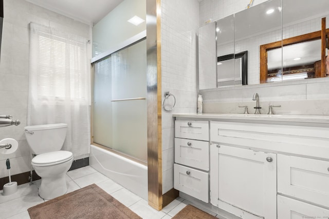 full bathroom featuring vanity, tile patterned floors, toilet, bath / shower combo with glass door, and tile walls