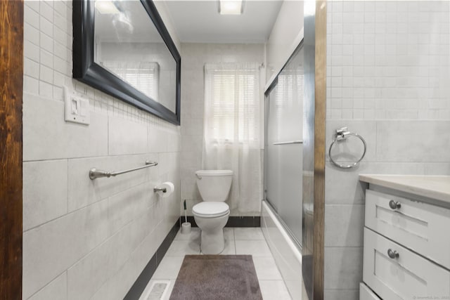 full bathroom featuring tile walls, vanity, toilet, tile patterned flooring, and shower / bath combination with glass door