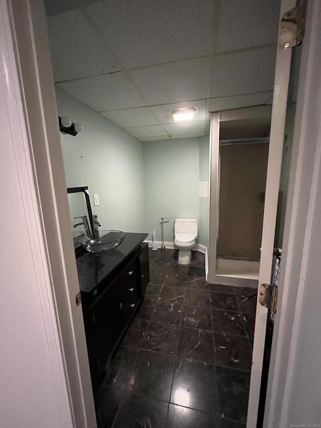 full bath with a shower stall, a paneled ceiling, vanity, toilet, and baseboards