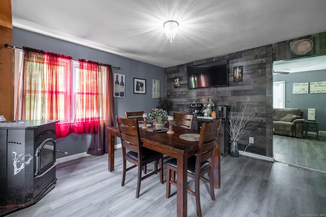 348 Harwinton Ave, Torrington, CT 06790 - dining area featuring a wood stove, wood finished floors, baseboards, and an accent wall