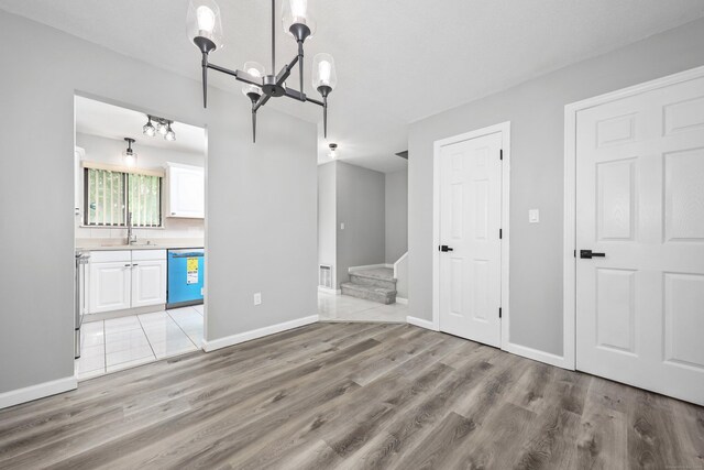 1400 Meriden Rd Apt 1-2, Waterbury, CT 06705 - unfurnished living room featuring a chandelier, light wood-style flooring, stairs, a sink, and baseboards