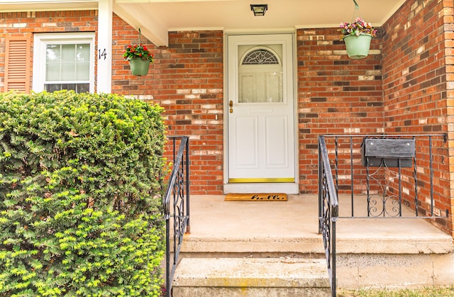 view of exterior entry with brick siding and covered porch