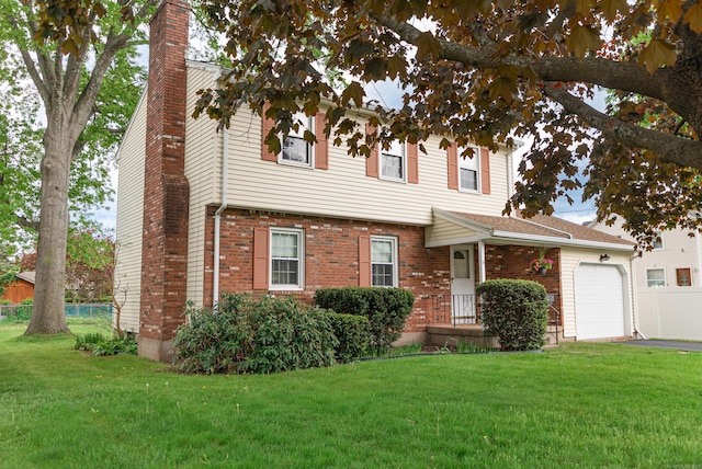 colonial-style house featuring a chimney, a garage, driveway, and brick siding