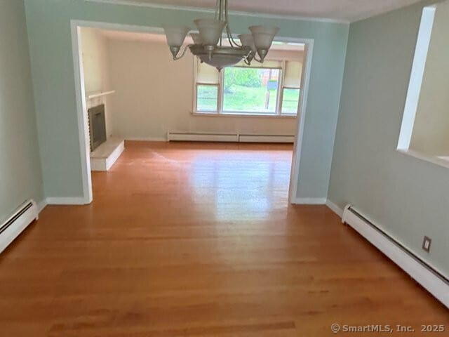 6 Spencer Pl, New Haven, CT 06515 - unfurnished dining area with a baseboard heating unit, baseboard heating, wood finished floors, a chandelier, and a fireplace with raised hearth