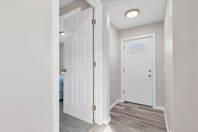 doorway featuring baseboards and light wood finished floors