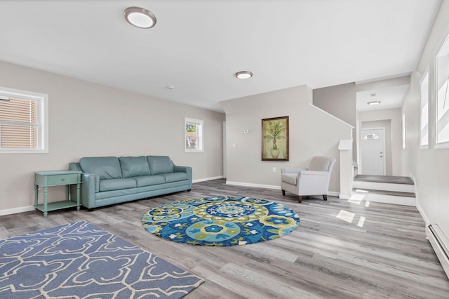 living area featuring a baseboard heating unit, wood finished floors, and baseboards