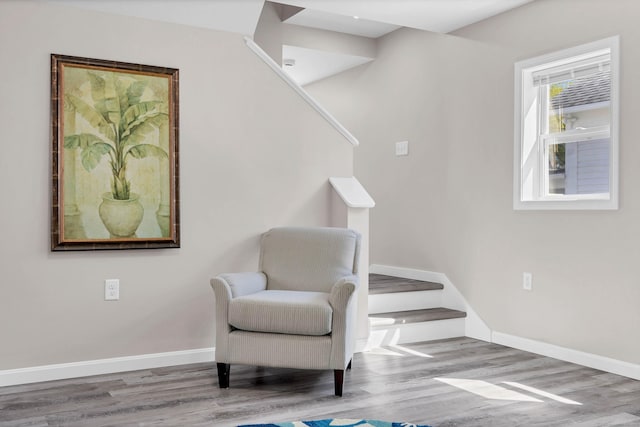 sitting room with stairs, wood finished floors, and baseboards