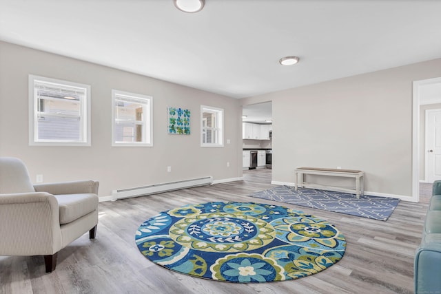 living area featuring a baseboard heating unit, wood finished floors, and baseboards