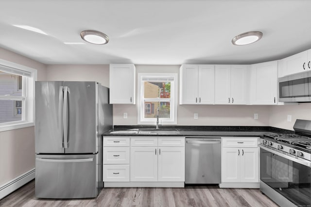 kitchen with stainless steel appliances, a baseboard heating unit, a sink, light wood-style floors, and white cabinets