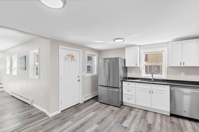 kitchen with appliances with stainless steel finishes, baseboard heating, a sink, and healthy amount of natural light