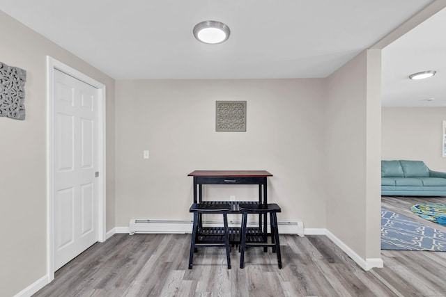 dining area with a baseboard heating unit, wood finished floors, and baseboards