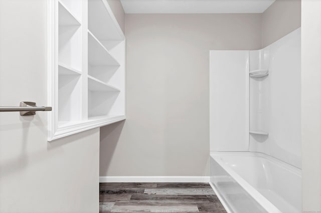 bathroom with wood finished floors, baseboards, and bathtub / shower combination