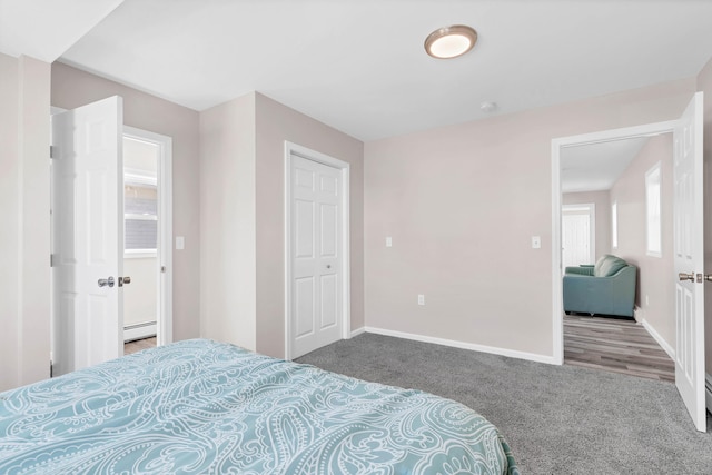 carpeted bedroom with a baseboard heating unit and baseboards