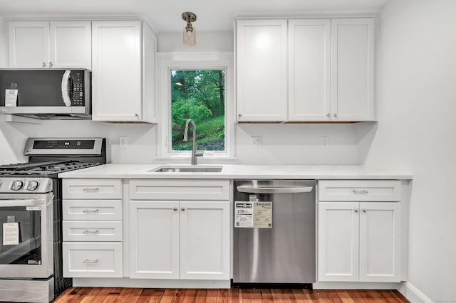 kitchen featuring stainless steel appliances, a sink, white cabinets, and light countertops