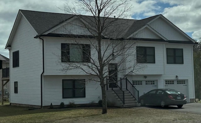 view of front of property featuring a garage, a shingled roof, driveway, and a front lawn