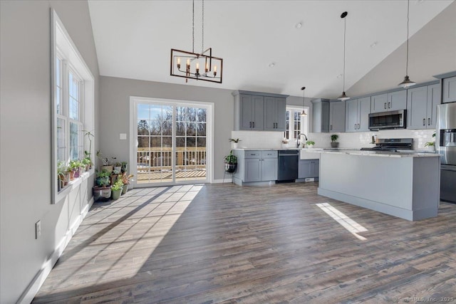 kitchen featuring appliances with stainless steel finishes, gray cabinets, high vaulted ceiling, a chandelier, and light countertops