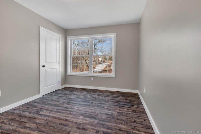 spare room with dark wood finished floors and baseboards