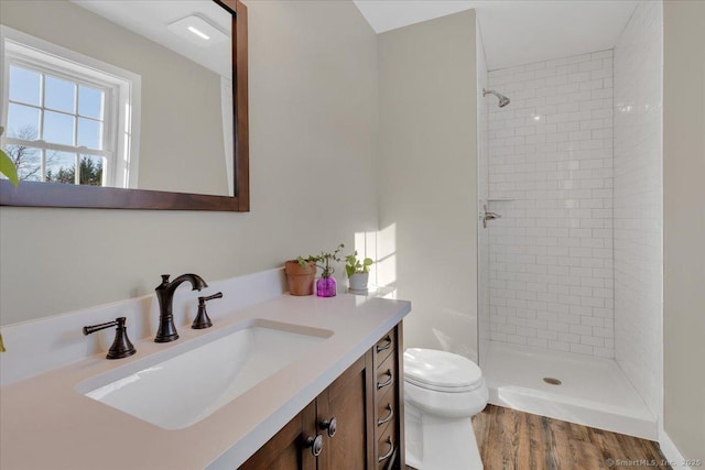 bathroom with tiled shower, vanity, toilet, and wood finished floors