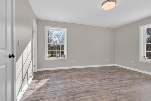 spare room with healthy amount of natural light, wood finished floors, and baseboards