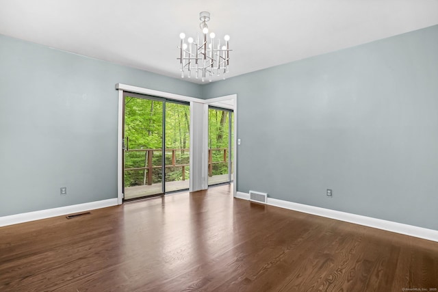 unfurnished room featuring a chandelier, baseboards, and wood finished floors