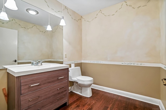 half bathroom with wood finished floors, vanity, toilet, and baseboards