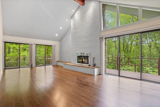 unfurnished living room featuring high vaulted ceiling, a brick fireplace, wood finished floors, beamed ceiling, and recessed lighting
