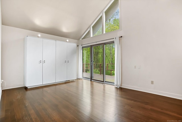 unfurnished bedroom featuring access to outside, dark wood finished floors, baseboards, high vaulted ceiling, and a closet
