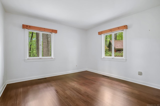 unfurnished room with dark wood finished floors and baseboards