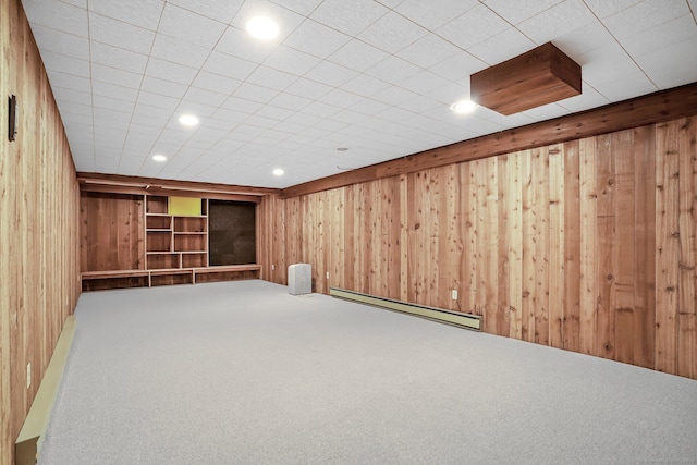 finished below grade area with a baseboard heating unit, wooden walls, carpet, and recessed lighting