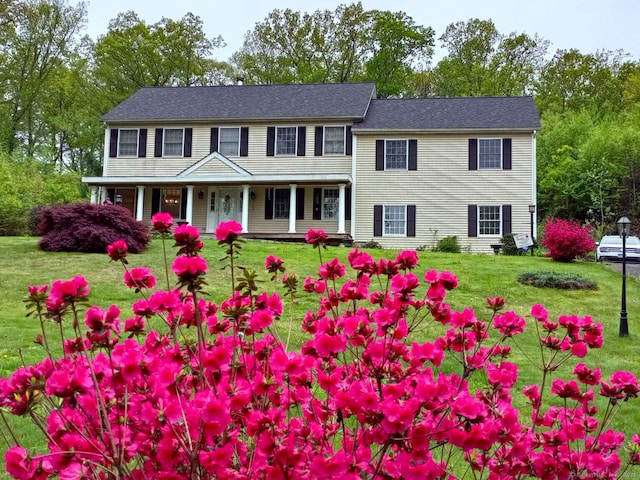 colonial-style house featuring a front yard and covered porch