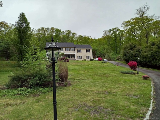 view of green lawn with a forest view