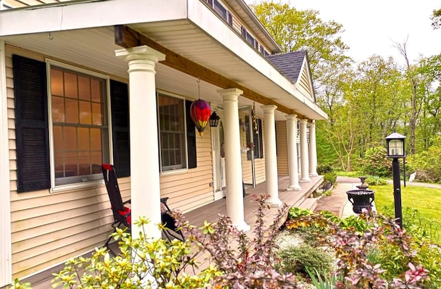 view of side of property with a porch and a shingled roof