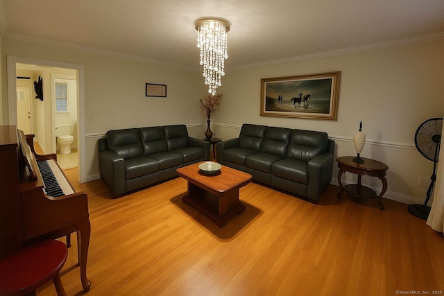 living room featuring ornamental molding, light wood finished floors, baseboards, and a chandelier