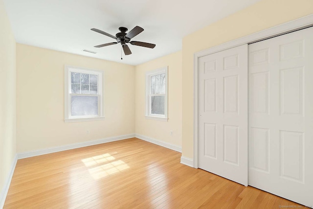 unfurnished bedroom with light wood-style flooring, a closet, baseboards, and a ceiling fan
