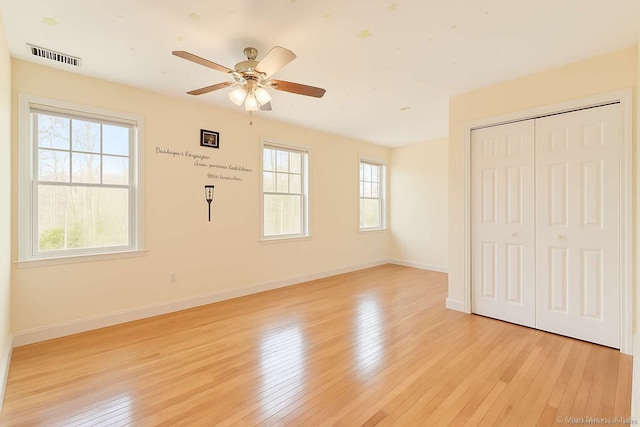 unfurnished bedroom featuring light wood-style floors, baseboards, a closet, and ceiling fan