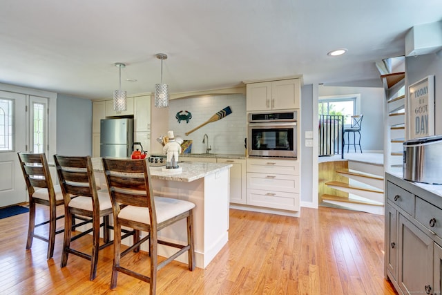 5 Quarry Rd, Stonington, CT 06355 - kitchen featuring appliances with stainless steel finishes, light wood finished floors, decorative backsplash, a kitchen bar, and recessed lighting