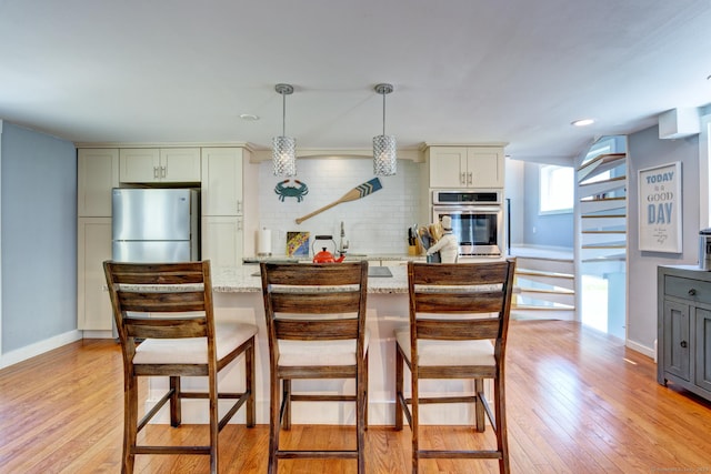 5 Quarry Rd, Stonington, CT 06355 - kitchen featuring appliances with stainless steel finishes, tasteful backsplash, light wood-type flooring, light stone counters, and decorative light fixtures