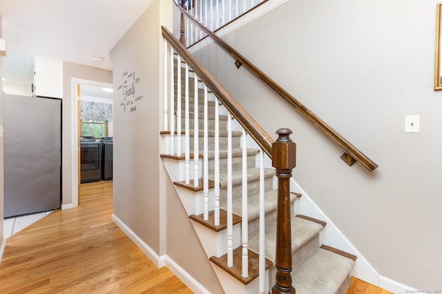 stairway featuring washer and dryer, wood finished floors, and baseboards