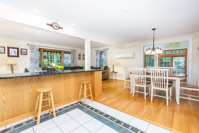 kitchen with a wall unit AC, dark stone countertops, a chandelier, tile patterned flooring, and recessed lighting