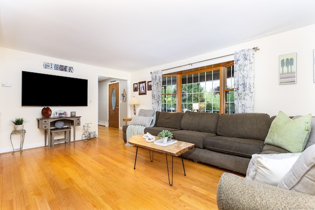 living room with a baseboard radiator, light wood-type flooring, and baseboards