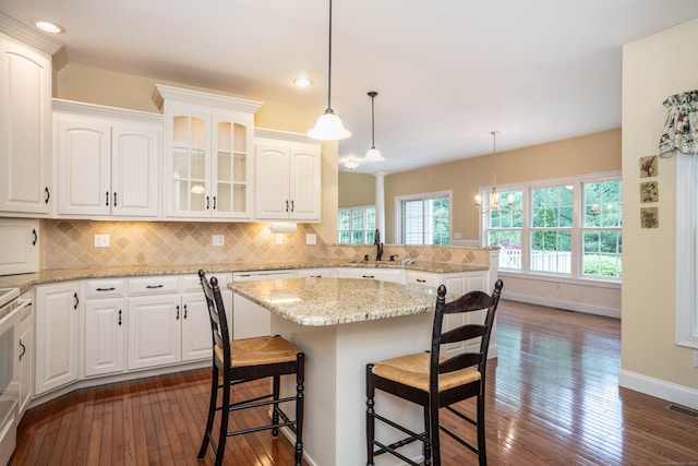 kitchen featuring baseboards, dark wood-type flooring, a peninsula, a breakfast bar, and a sink