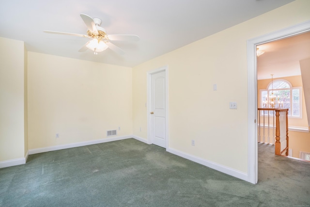 carpeted empty room featuring a ceiling fan, a chandelier, and baseboards