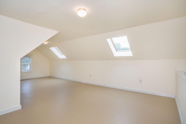 bonus room with a skylight, lofted ceiling, and baseboards