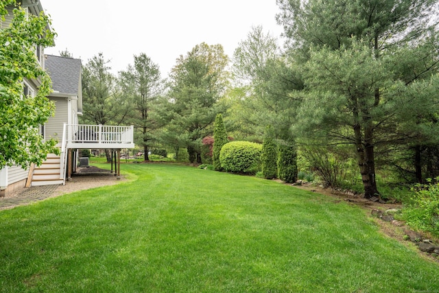 view of grassy yard with stairs and a deck