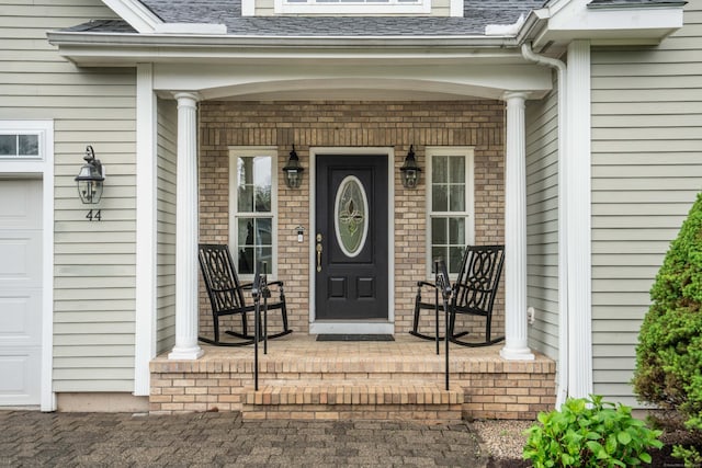 entrance to property with covered porch and roof with shingles